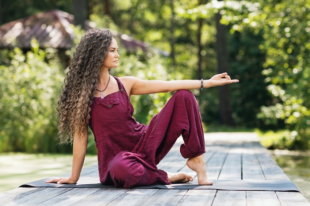 Vrouw beoefenen van yoga zittend op een mat met mudra in het park op een zonnige ochtend