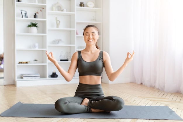 Vrouw beoefent yoga lotus pose binnen thuis