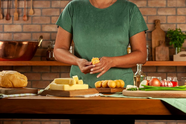 Vrouw bereidt Braziliaanse kaas gevulde kroket bolinha de queijo op een houten tafel