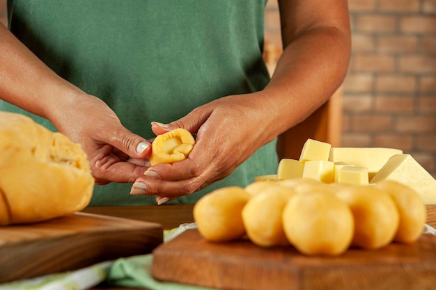 Vrouw bereidt Braziliaanse kaas gevulde kroket bolinha de queijo op een houten tafel