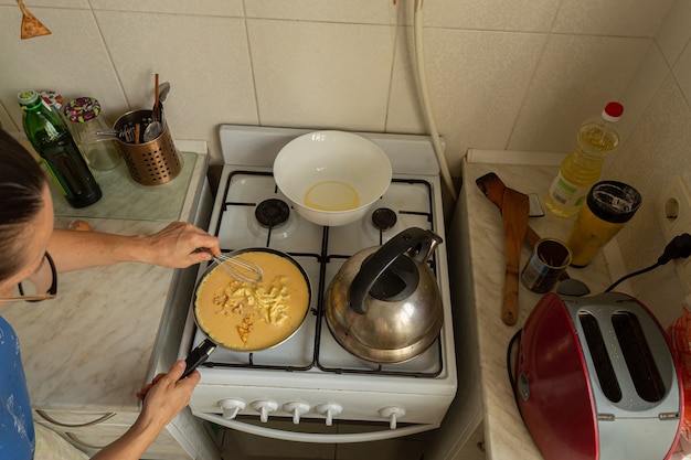Vrouw bereidt een omelet op een gasfornuis.