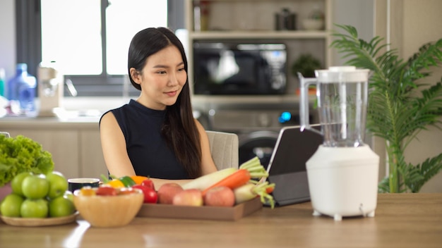 Vrouw bereidt haar menu voor gezonde dranken in de keuken en leest het recept op de online website op tablet