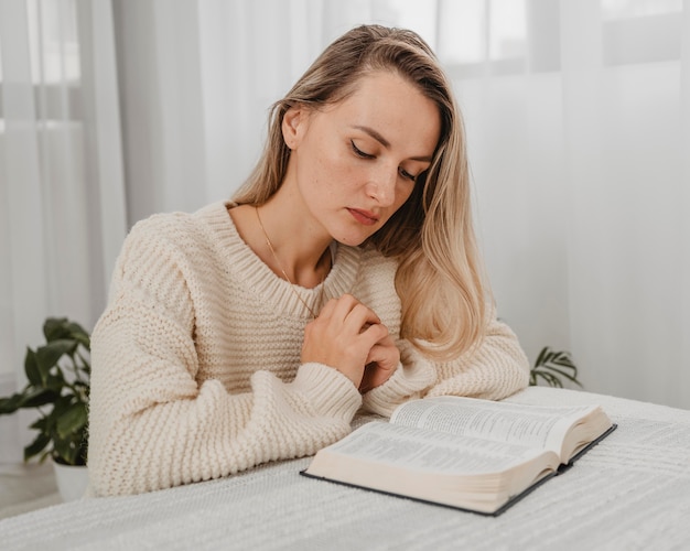 Vrouw bidden met Bijbel thuis