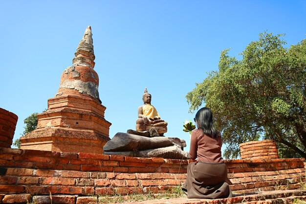 Vrouw bidden voor Boeddha beeld bij Wat Phra Ngam tempelruïnes in Thailand