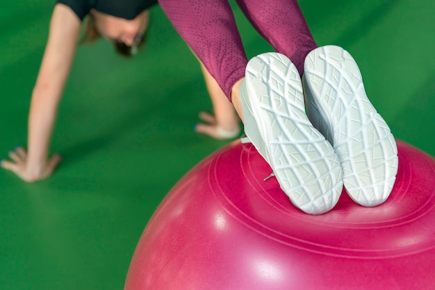 Vrouw bij de gymnastiek die plank met pilatesbal doet