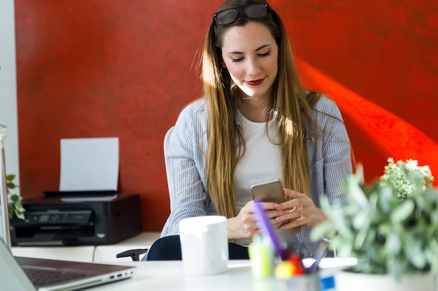 &quot;Vrouw bij de werkplek browsing telefoon&quot;