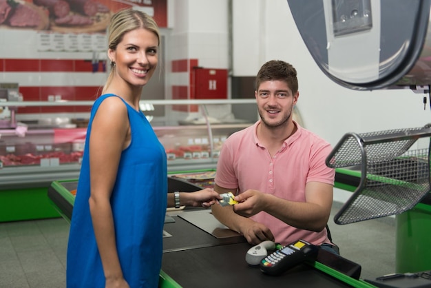 Vrouw bij kassa betalen met creditcard in supermarkt