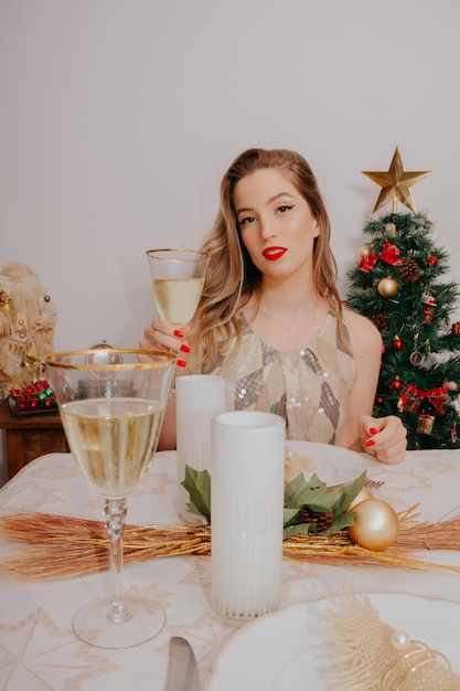 Vrouw bij kerstdiner met mousserende wijn en cadeautjes