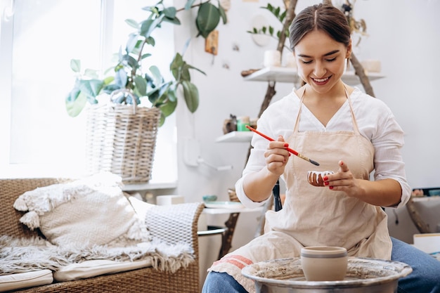 Vrouw bij pottenbakkersles leert keramische kan versieren