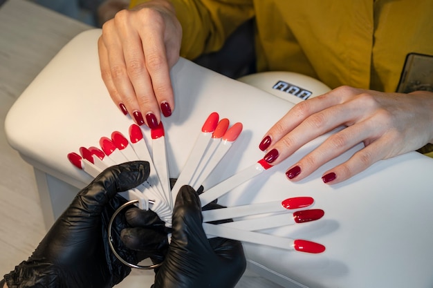 Vrouw bij spijkerstudio die kleur van nagellak kiest. Gellak. Nagellak in verschillende kleuren.