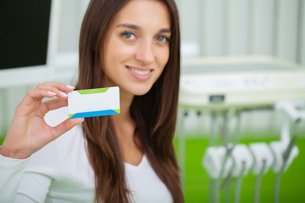 Vrouw bij tandkliniek die leeg adreskaartje houden