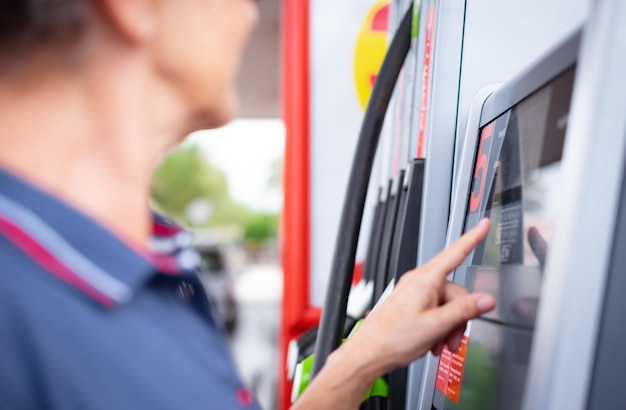 Vrouw bij zelfbedieningsbrandstofpomp in Europese tankstationtypen op het display het vereiste bedrag inflatie prijsverhoging economie speculatie concept