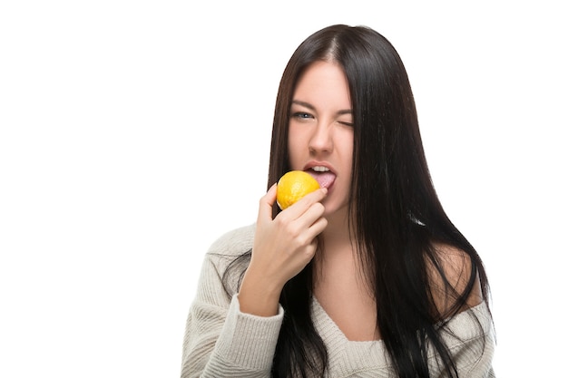 Vrouw bijt om verse citroen te eten. Emotie van walging op zuur