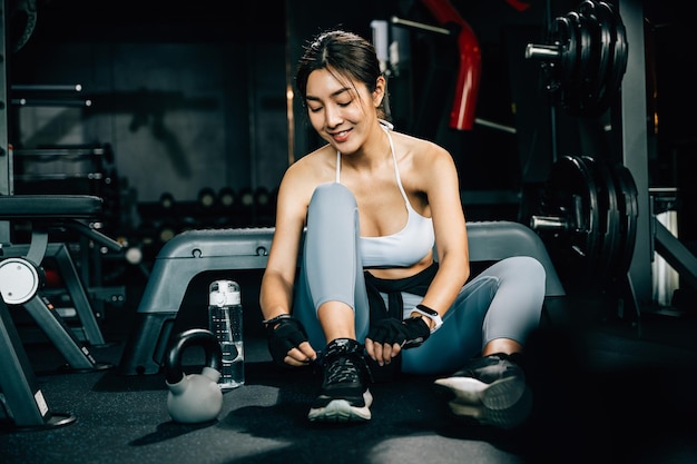 Vrouw bindt de veters van haar hardloopschoen met een shaker fles water De opname benadrukt het belang van gehydrateerd blijven tijdens het sporten