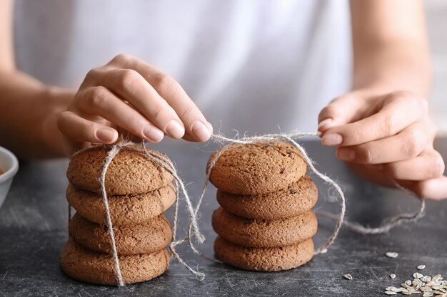 Vrouw bindt heerlijke havermoutkoekjes met touw op keukentafelclose-up