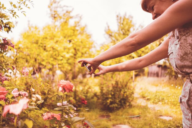 Vrouw bloemist maakt een foto van bloemen op haar telefoon in de tuin