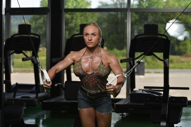 Vrouw bodybuilder werkt aan haar borst met kabelovergang in sportschool