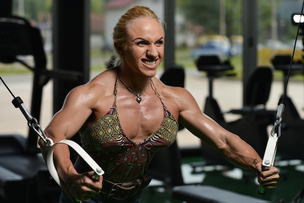 Vrouw bodybuilder werkt aan haar borst met kabelovergang in sportschool