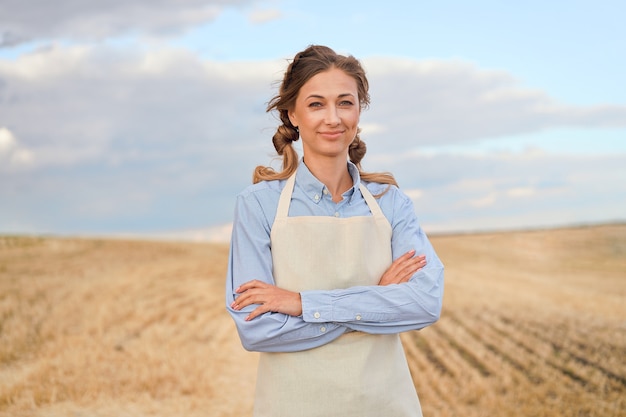 Vrouw boer schort staande landbouwgrond glimlachen Vrouwelijke agronoom specialist landbouw agribusiness Gelukkig positieve blanke werknemer landbouwgebied