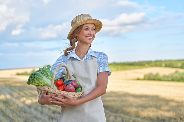 Vrouw boer strooien hoed schort staande landbouwgrond glimlachen Vrouwelijke agronoom specialist landbouw agribusiness Gelukkig positieve blanke werknemer landbouwgebied