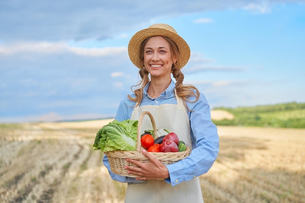 Vrouw boer strooien hoed schort staande landbouwgrond glimlachen Vrouwelijke agronoom specialist landbouw agribusiness Gelukkig positieve blanke werknemer landbouwgebied