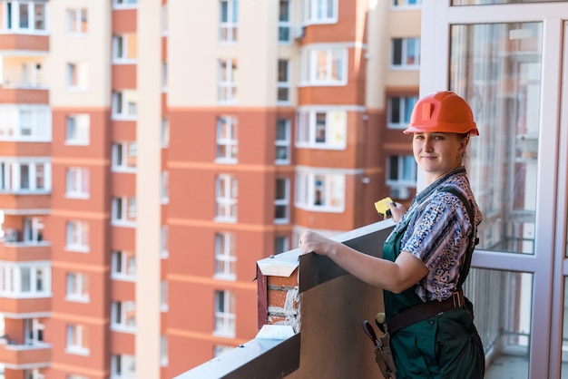 Vrouw bouwer poseren op balkon in nieuw appartement