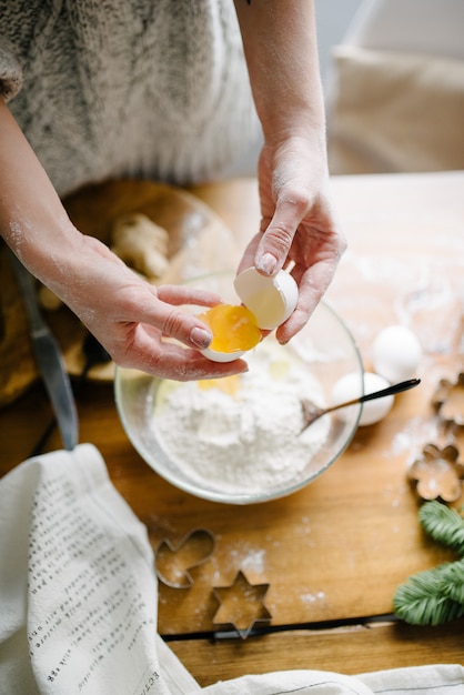 Vrouw breekt een ei en voegt toe aan de bloem. Proces koken.