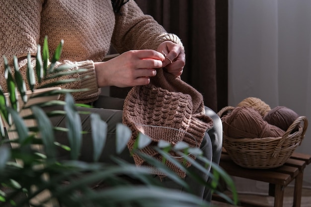 Vrouw breit een wollen trui op breinaalden Accessoires in de buurt om met de hand te breien in rieten mand