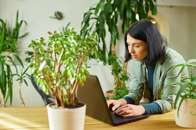 Vrouw browsen informatie over kamerplant vrouwelijke gebruik laptop