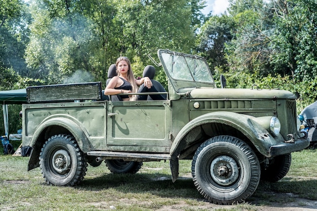 Vrouw buiten zittend op de motorkap van militaire auto