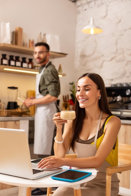 Vrouw cappuccino drinken en werken op laptop na werkdag