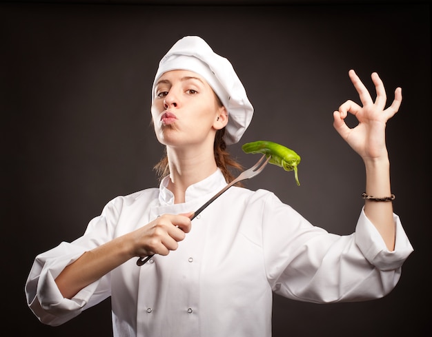 Foto vrouw chef-kok met een groene peper met een vork