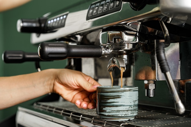 Vrouw coffeeshop werknemer koffie op professionele koffiemachine close-up voorbereiden