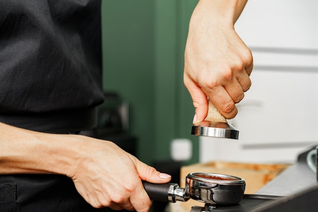 Vrouw coffeeshop werknemer koffie op professionele koffiemachine voorbereiden