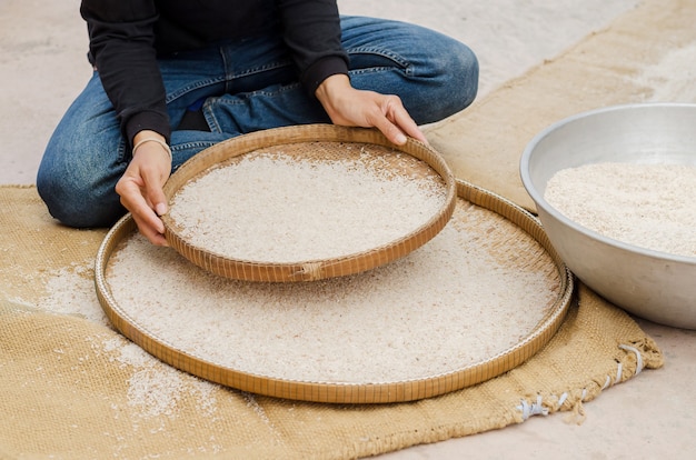 Foto vrouw concurrerende ziften rijst met behulp van bamboe mandenmakerswerk buiten