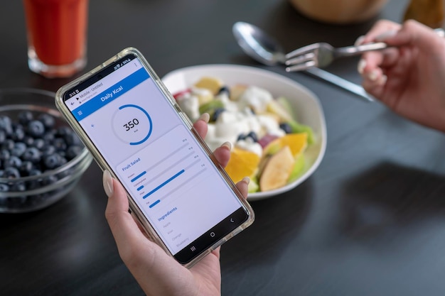 Vrouw controleert calorieën en voedingsstoffen app op haar telefoon tijdens het eten professionele voedingsdeskundige
