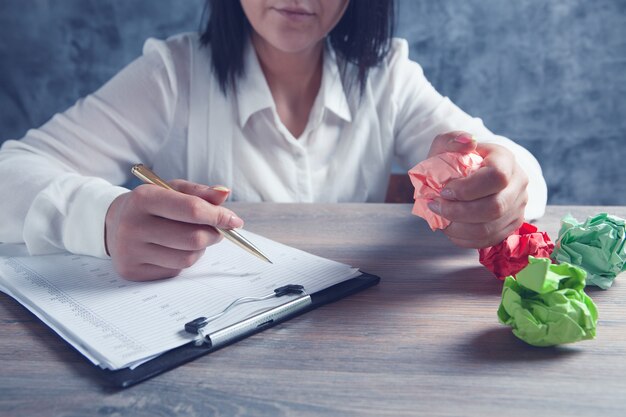 Vrouw controleert papieren en houdt verfrommeld papier vast