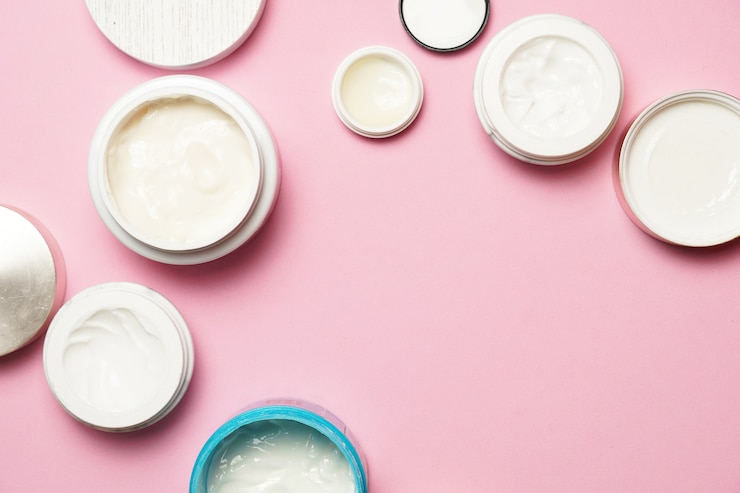 Vrouw crèmes op roze platte achtergrond, gezicht en lichaam crèmes. plat liggen. schoonheids- en huidverzorgingsconcept