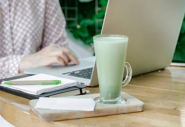 Vrouw cup groene matcha latte koffie thee glas werkplek cafe terassa huis freelancer