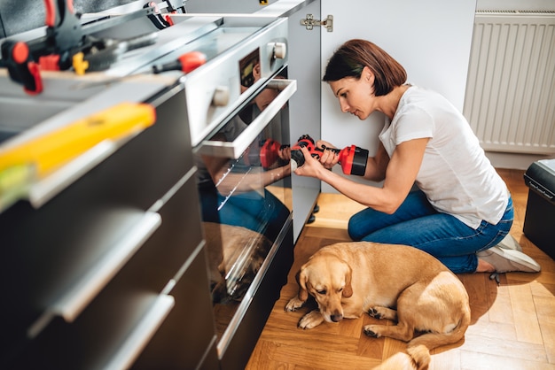 Vrouw de bouwkeuken en het gebruiken van een draadloze boor