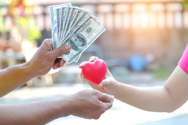 Vrouw de hand geven rood hartsymbool met het wisselen van geld van iemand Premium Foto