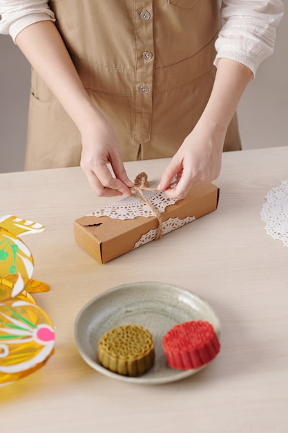 Vrouw decoreert doos met zelfgemaakte mooncakes met touw om cadeau te geven aan haar familieleden en ...