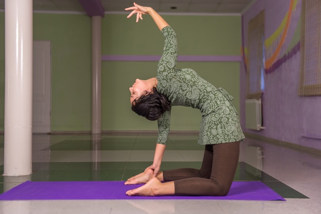 Vrouw demonstreert yogaposities in fitness class./Yoga leerling yoga onderwijzen in een studio.