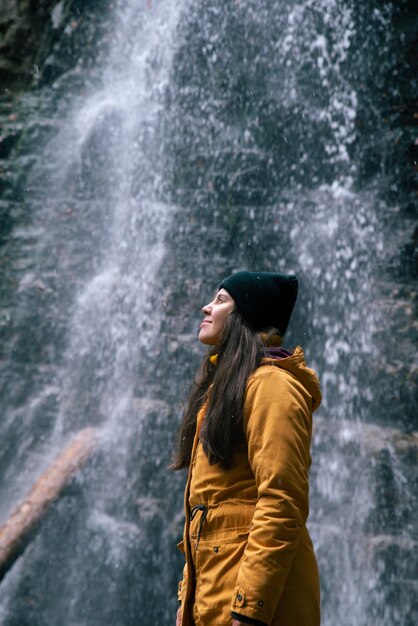 Vrouw dichtbij waterval in bosherfstseizoen