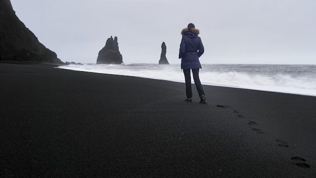 Vrouw die aan de kust van Reynisfjara loopt