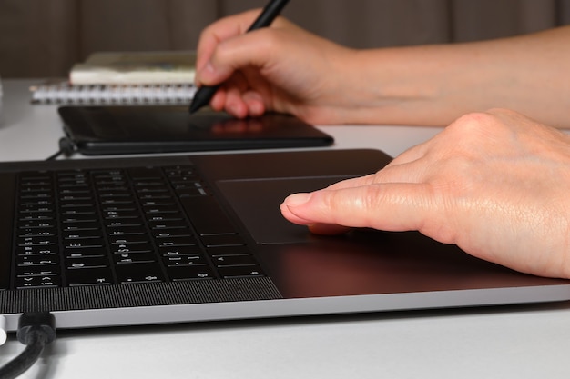 Vrouw die aan een laptop en een grafisch tablet werkt