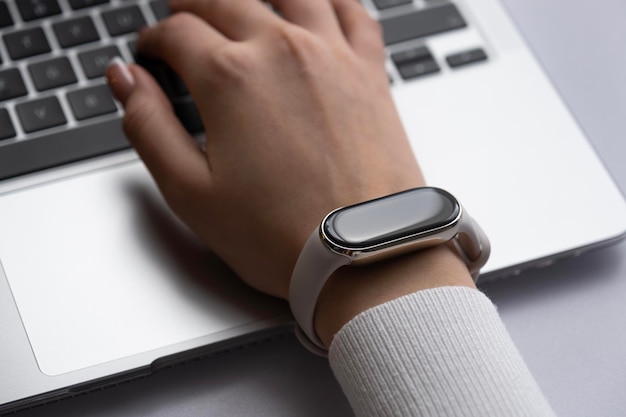 Foto vrouw die aan een laptop werkt met een slim horloge aan haar pols