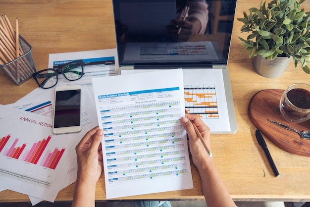 Foto vrouw die aan een thuisbureau werkt met behulp van een laptop, een zakelijk financieel document, een grafiekgrafiekbureau