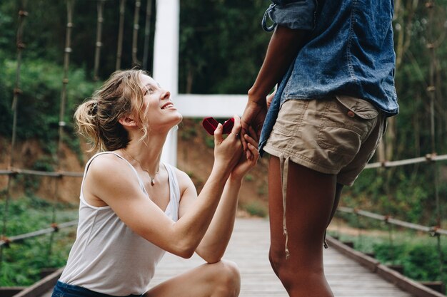 Vrouw die aan haar gelukkige vriendin in openlucht liefde en huwelijksconcept voorstellen