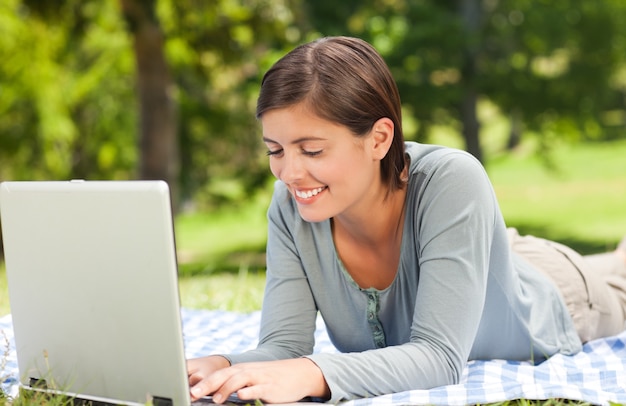 Vrouw die aan haar laptop in het park werkt